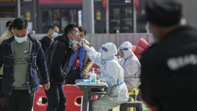 A health worker (centre R) takes a swab sample from a man to be tested for the Covid-19 coronavirus at a makeshift testing site along a street in Beijing on March 15, 2022. (Photo by Jade GAO / AFP)