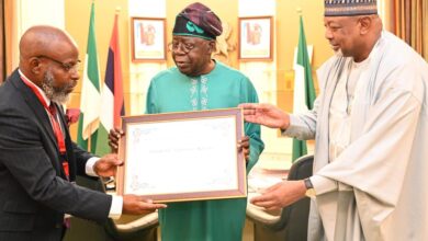 Prof. Adenle (l) presenting the award to President Tinubu